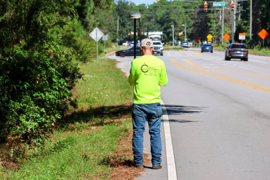 Land surveyor using GPS equipment along roadway for right-of-way surveying